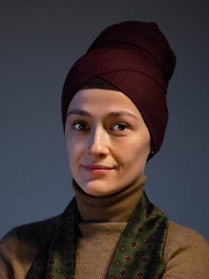 Woman wearing a purple headscarf against a dark background